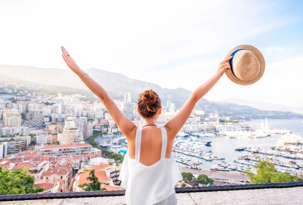 woman from the back with arms in the air holding a hat